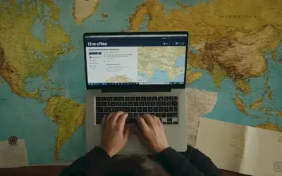 Persona escribiendo en su portátil mientras mira un mapa. El texto está en español. En inglés: ¿Cómo cambiaron las alianzas internacionales después de la guerra? Un análisis profundo.